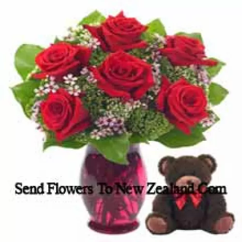7 roses rouges avec quelques fougères dans un vase en verre accompagnées d'un mignon ours en peluche de 14 pouces de hauteur