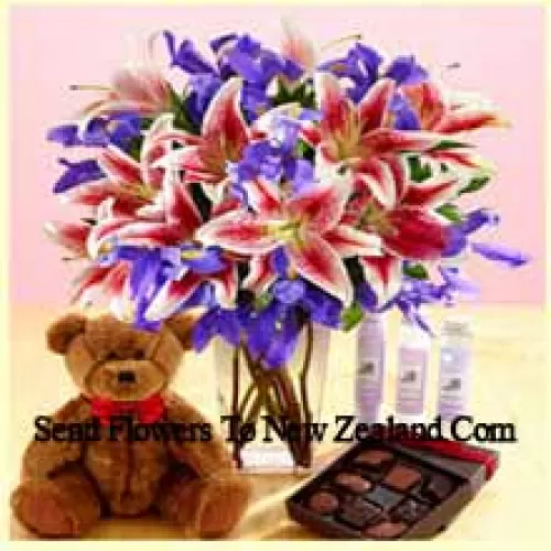 Lys roses et fleurs violettes assorties disposées magnifiquement dans un vase en verre, un mignon ourson brun de 12 pouces de hauteur et une boîte de chocolats importés
