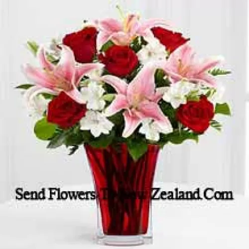 6 roses rouges et 5 lis roses avec des remplisseurs saisonniers dans un beau vase en verre