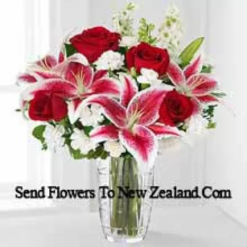 Roses rouges, lys roses avec des fleurs blanches assorties dans un vase en verre